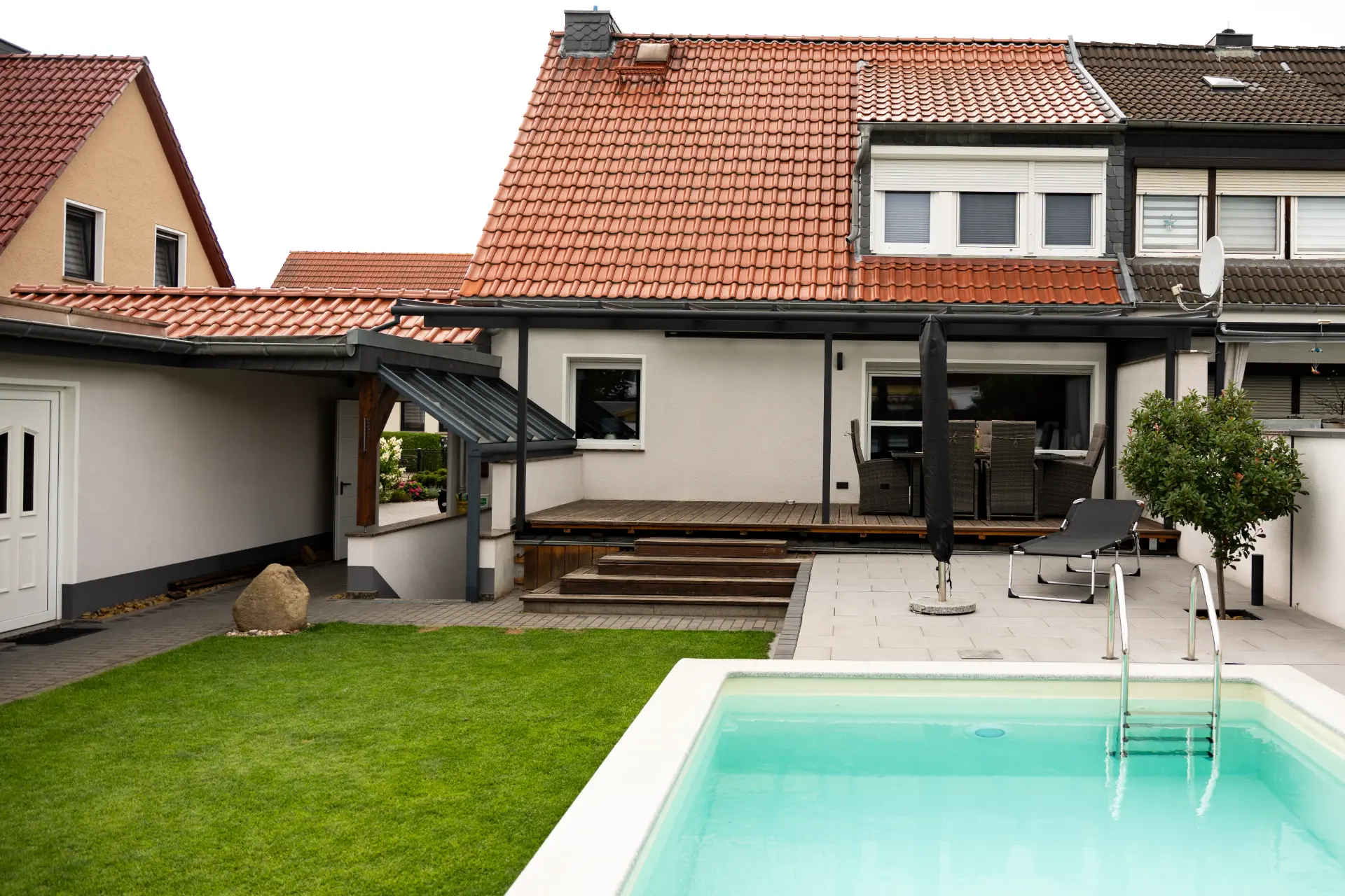 Terrassendach über einer Holzterrasse mit Stufen an einem Reihenhaus