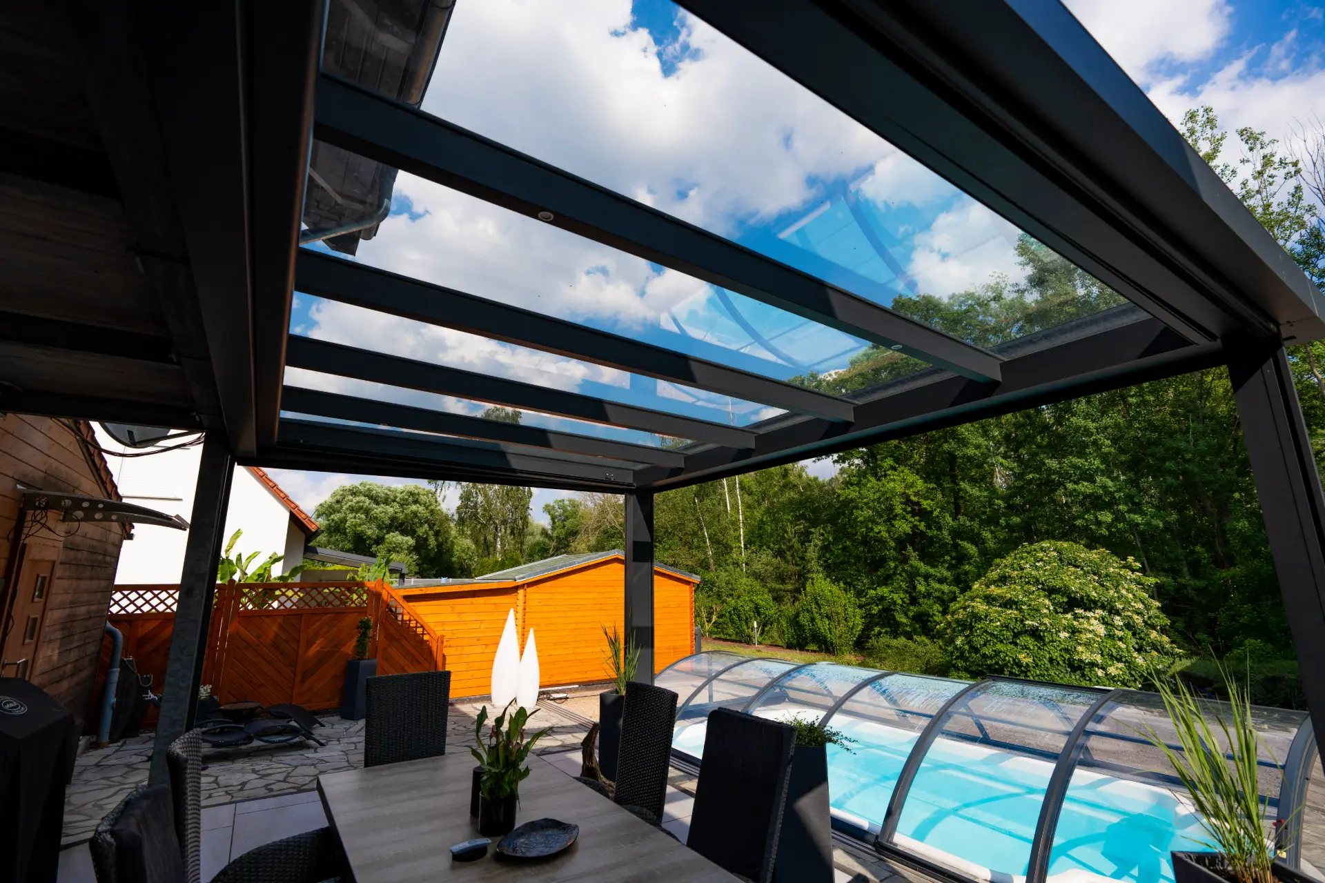 Blick von unten durch ein Glasdach aus Aluminium in den Himmel über einer Terrasse