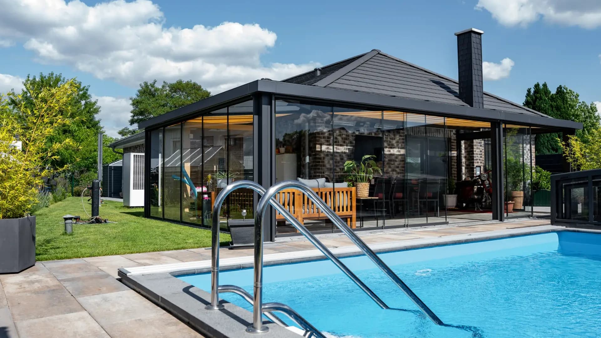 Wintergarten mit Ganzglasschiebeanlage neben dem Pool eines Einfamilienhauses