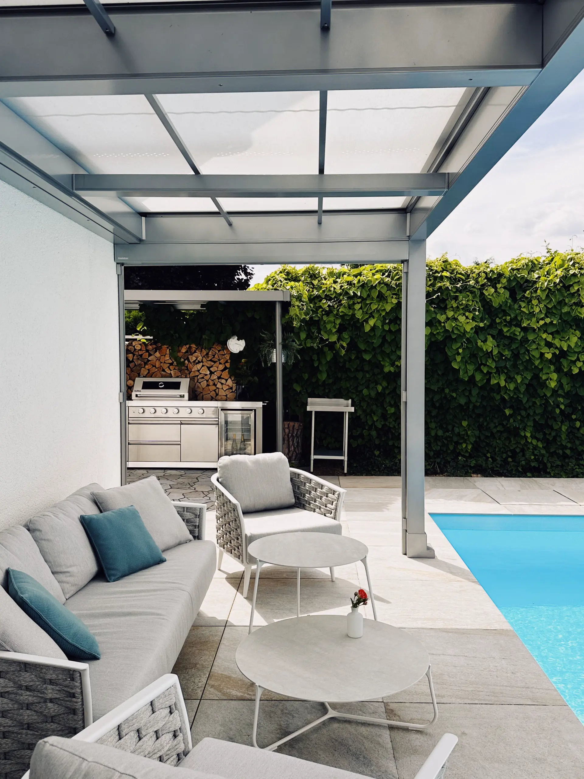 Terrassendach aus Aluminium über Loungebereich und Außenküche neben einem Pool