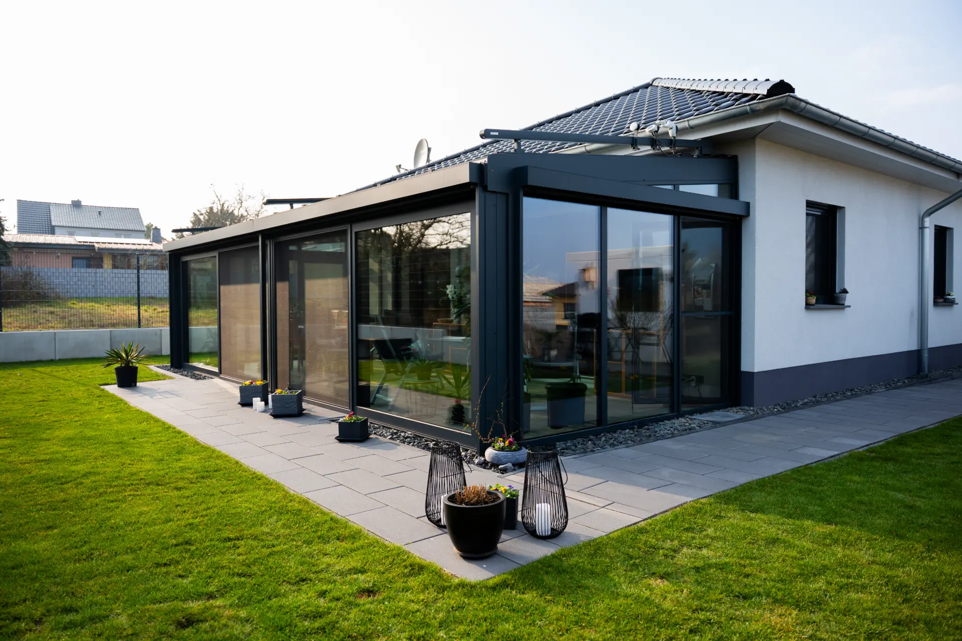 Wintergarten mit großen Glasschiebeelementen an einem Bungalow im Abendlicht