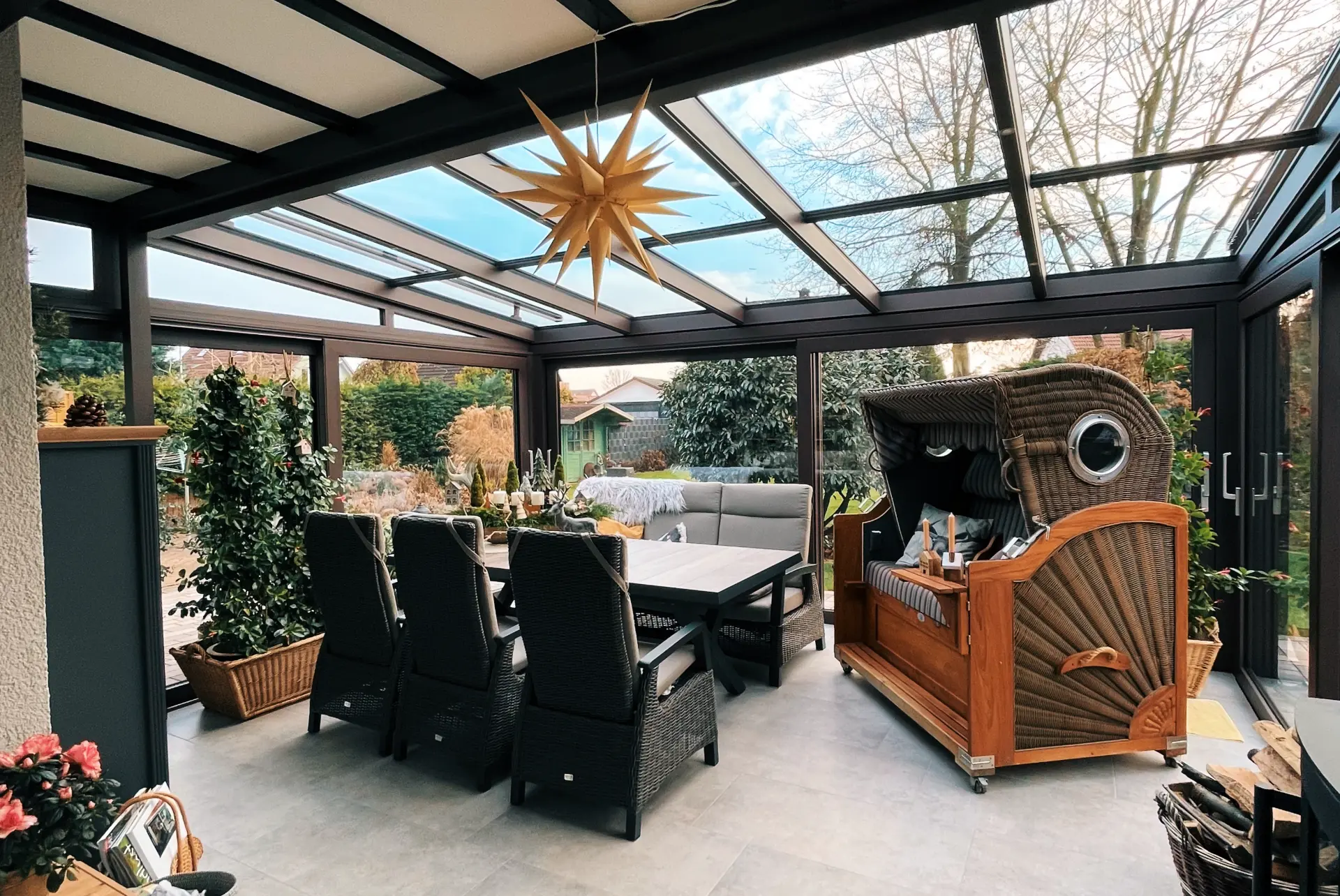 Wintergarten mit Rattan-Strandkorb und Herrnhuter Stern über dem Esstisch