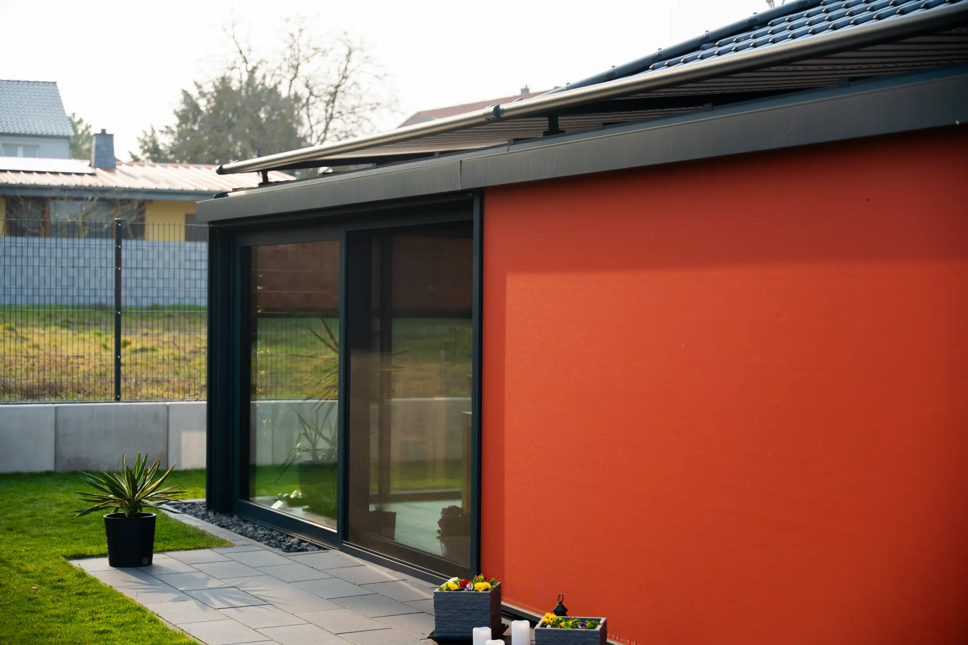 Terrassenecke mit ausgefahrenem orangefarbenem Sichtschutz-Screen an einem Bungalow